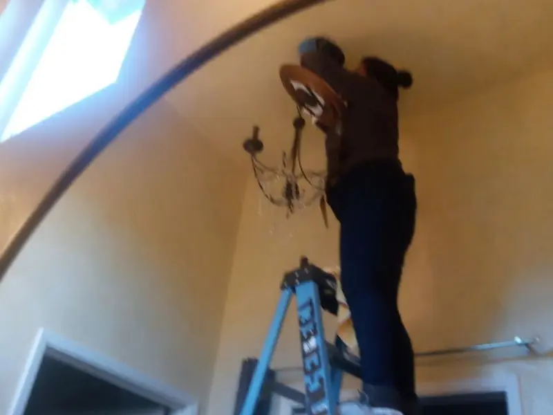 Electrician installing a chandelier in a Evergreen residence